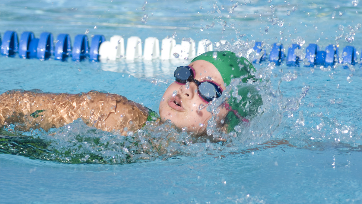 A girl swims with googles and a swimcap.