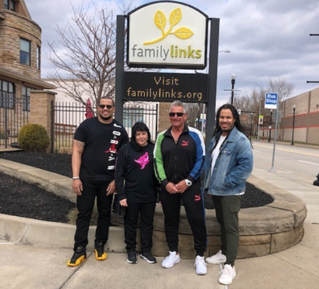 Four people smile in front of the Familylinks sign